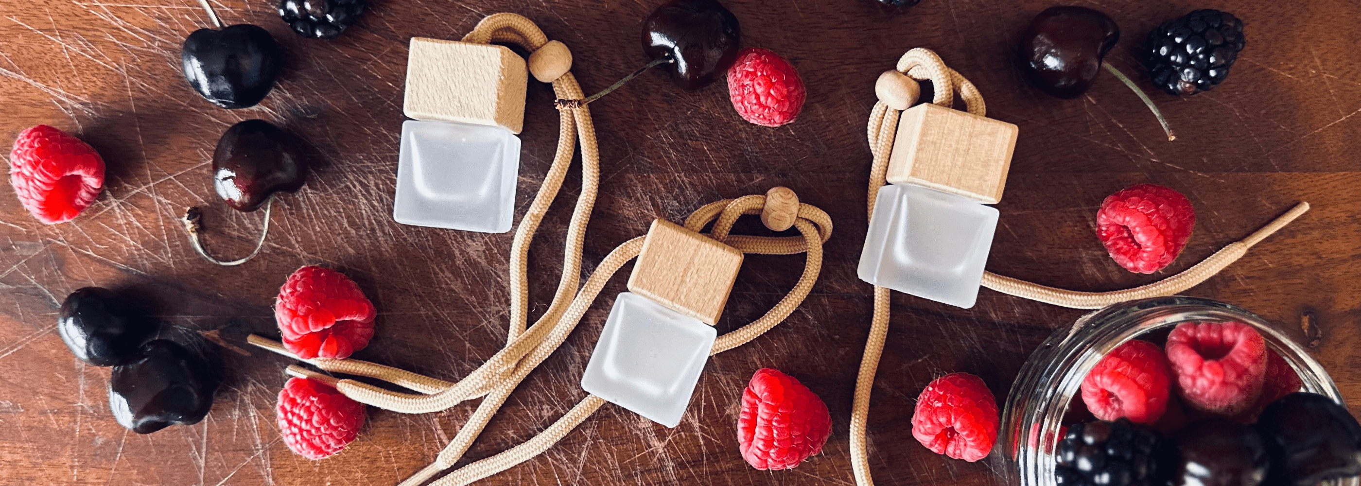 Black Cherry Car Diffuser - Frosted car diffuser bottles with wooden lids surrounded by black forest fruits