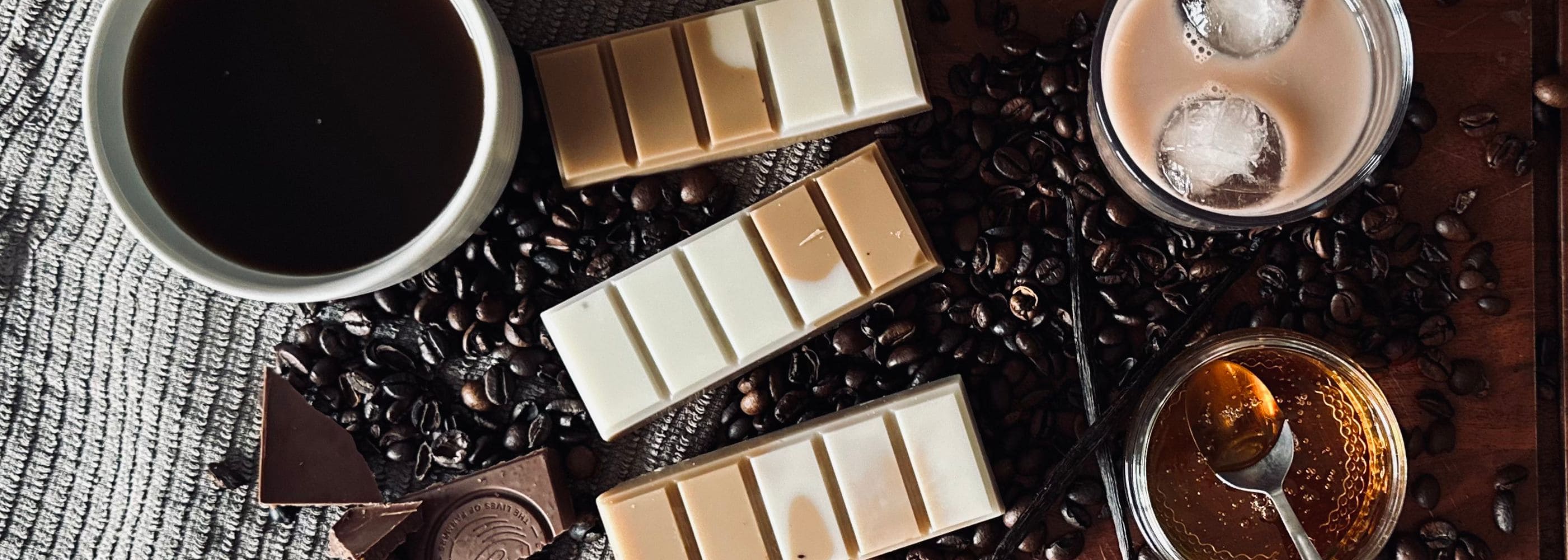 Irish Coffee wax melts - brown and white soy wax melts surrounded by coffee beans, black coffee and a latte