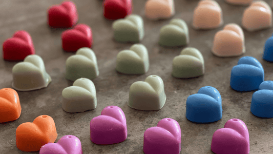 a range of multi coloured soy heart wax melts laid out in a rainbow style