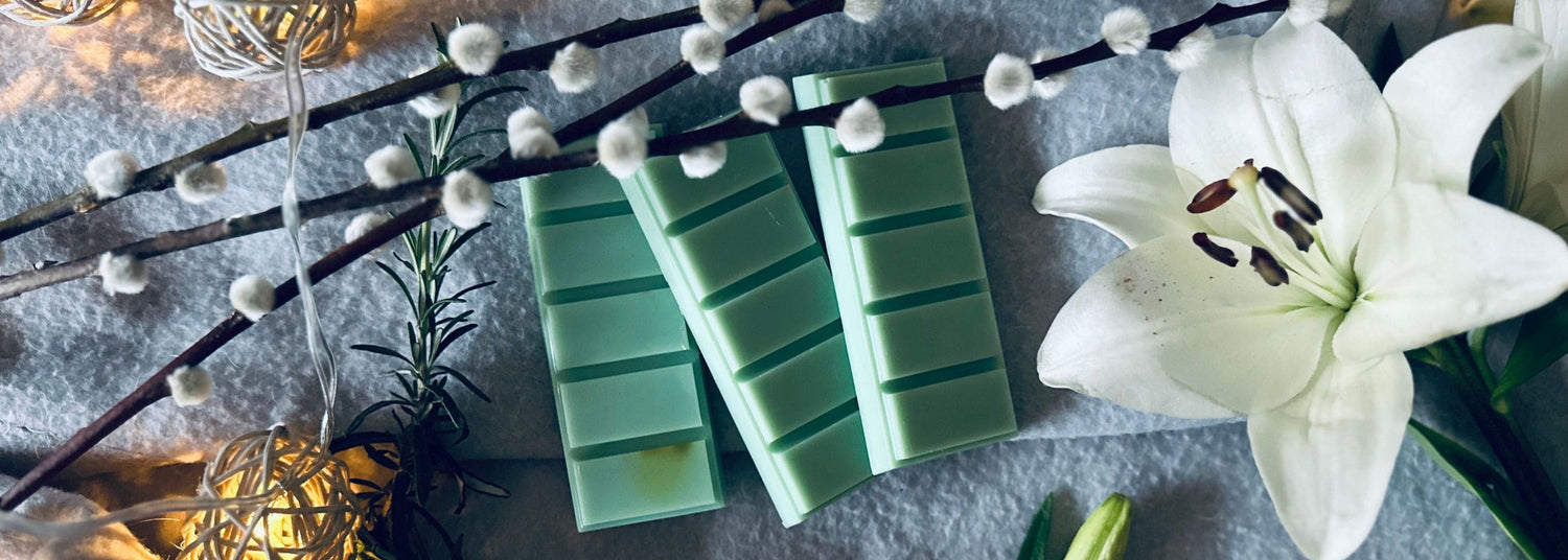 enchanted forest wax melts - green soy wax melts on a cotton blanket sat next to a white lily