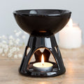 Black modern gothic styled ceramic oil burner with a lit tealight candle on a wooden surface.