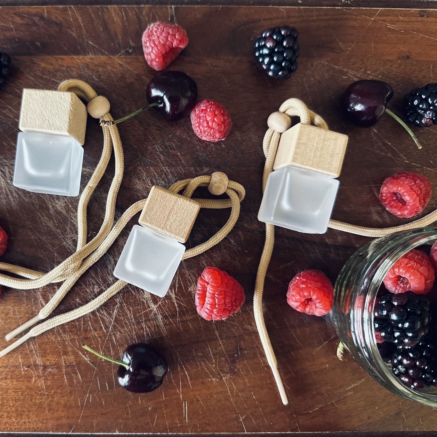 Fruity scented car diffusers surrounded. by black cherries, blackberries and raspberries