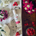 Black Raspberry & Peppercorn scented luxury frosted glass room spray surrounded by fresh flowers, peppercorns and raspberries sitting on a cosy blanket