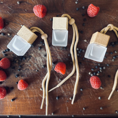 luxurious fruity scented car diffusers surrounded by fresh raspberries and black peppercorns