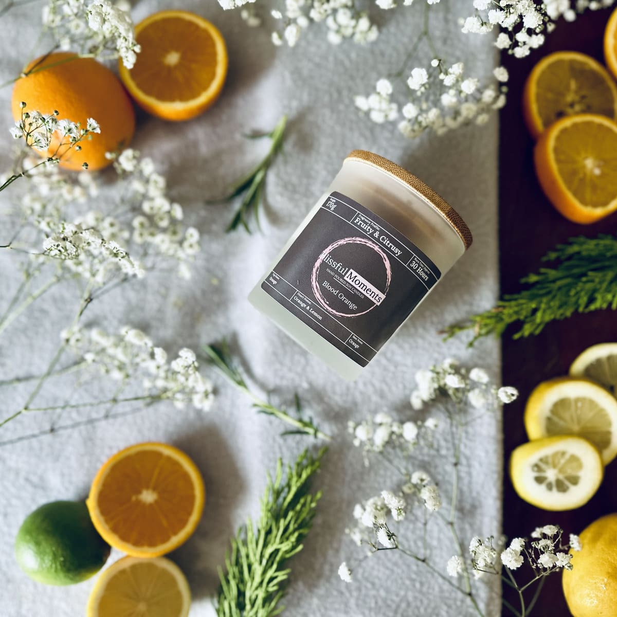 Citrus orange scented soy candle surrounded by citrus fruits and white flowers