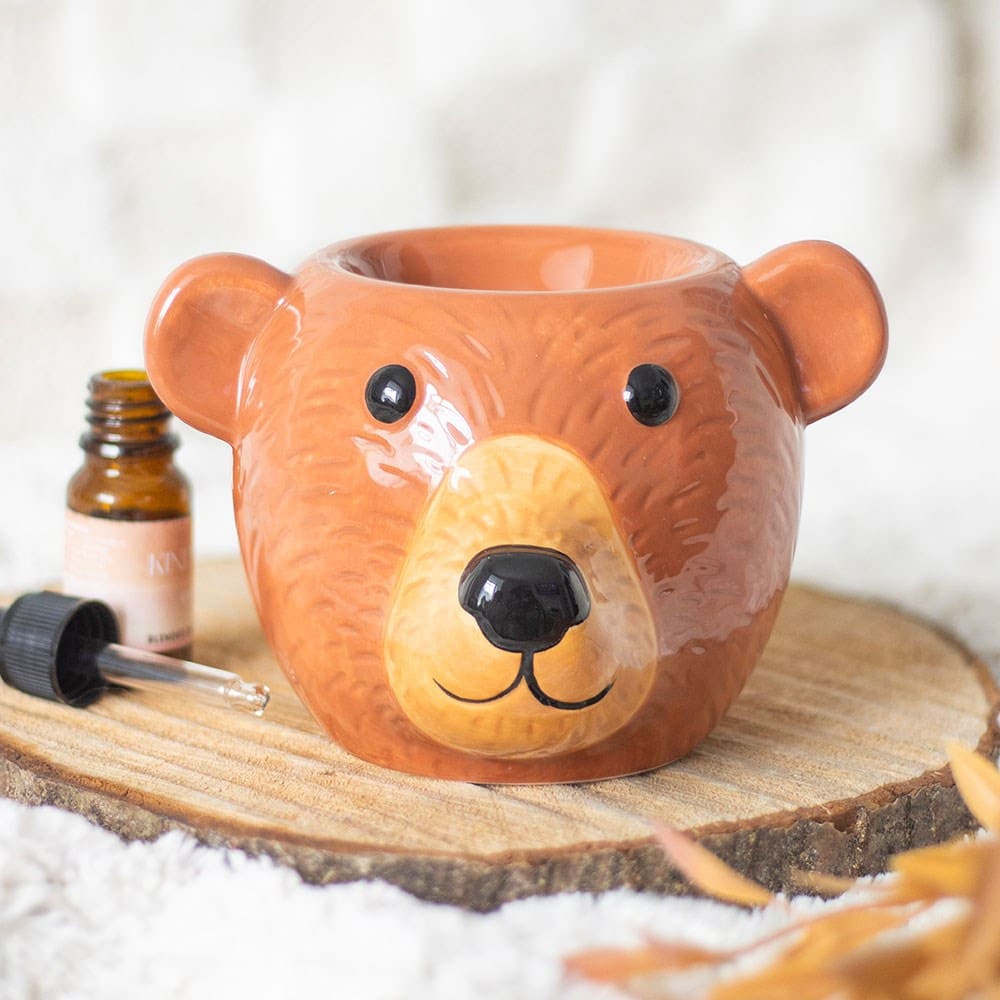 Teddy Bear-shaped wax melt burner on a wooden surface with a bottle of essential oil and dropper.