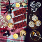 Christmas Cookies scented snapbar wax melts on a festive plaid cloth with tealights, chestnuts, pinecones, and decorative lights.
