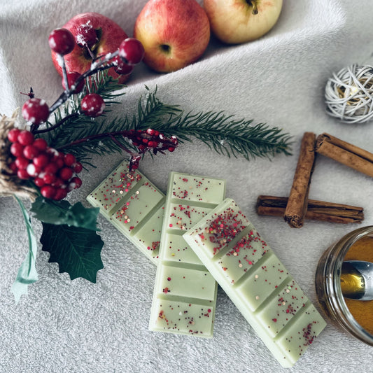 Apple and Cinnamon scented cosy wax melts surrounded by crisp apples, cinnamon sticks and honey sitting on a white cosy blanket