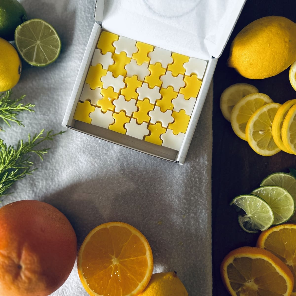 Citrus lemon scented yellow and white jigsaw puzzle shaped wax melts surrounded by citrus fruits