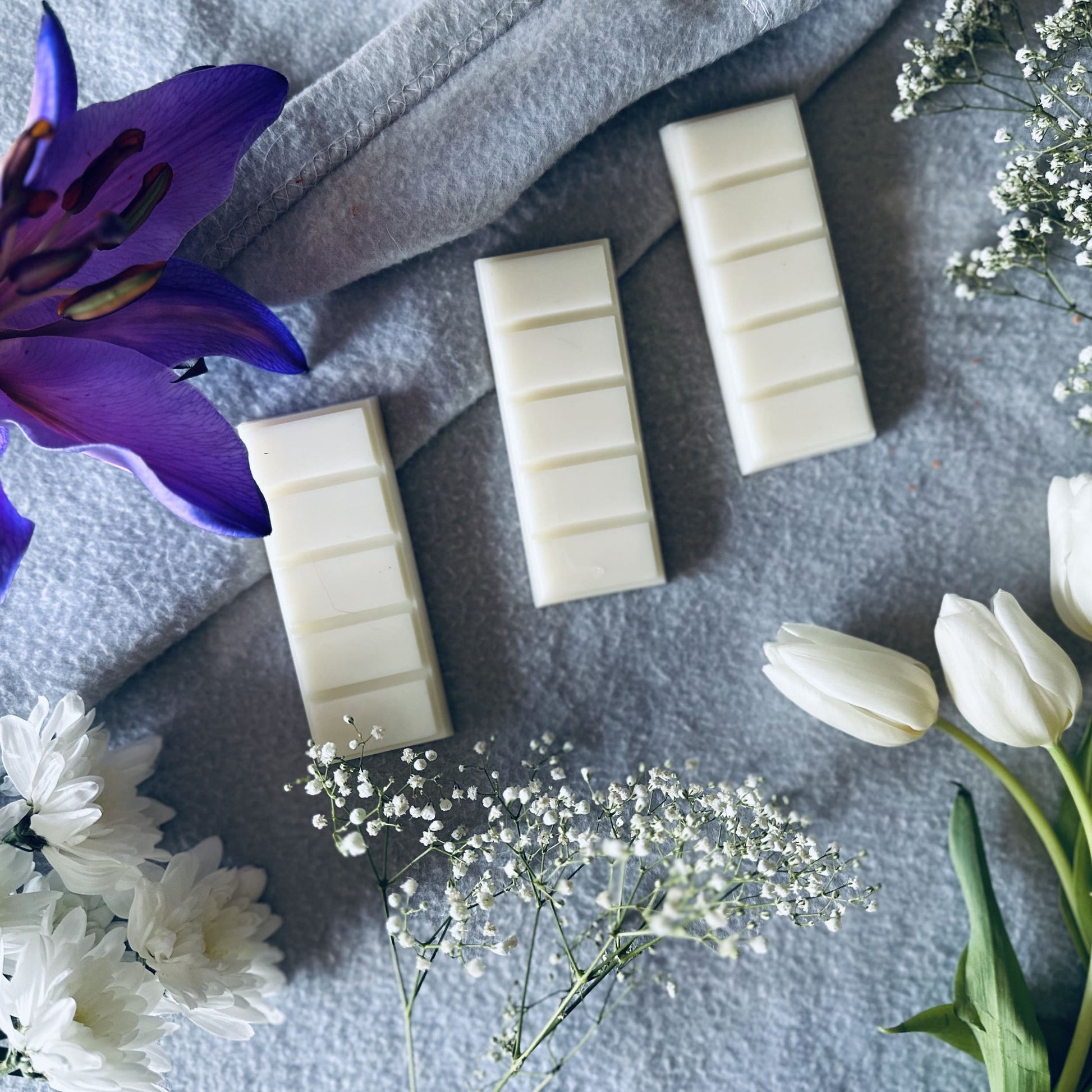 Clean cotton scented soy wax melts surrounded by purple lilies and white tulips