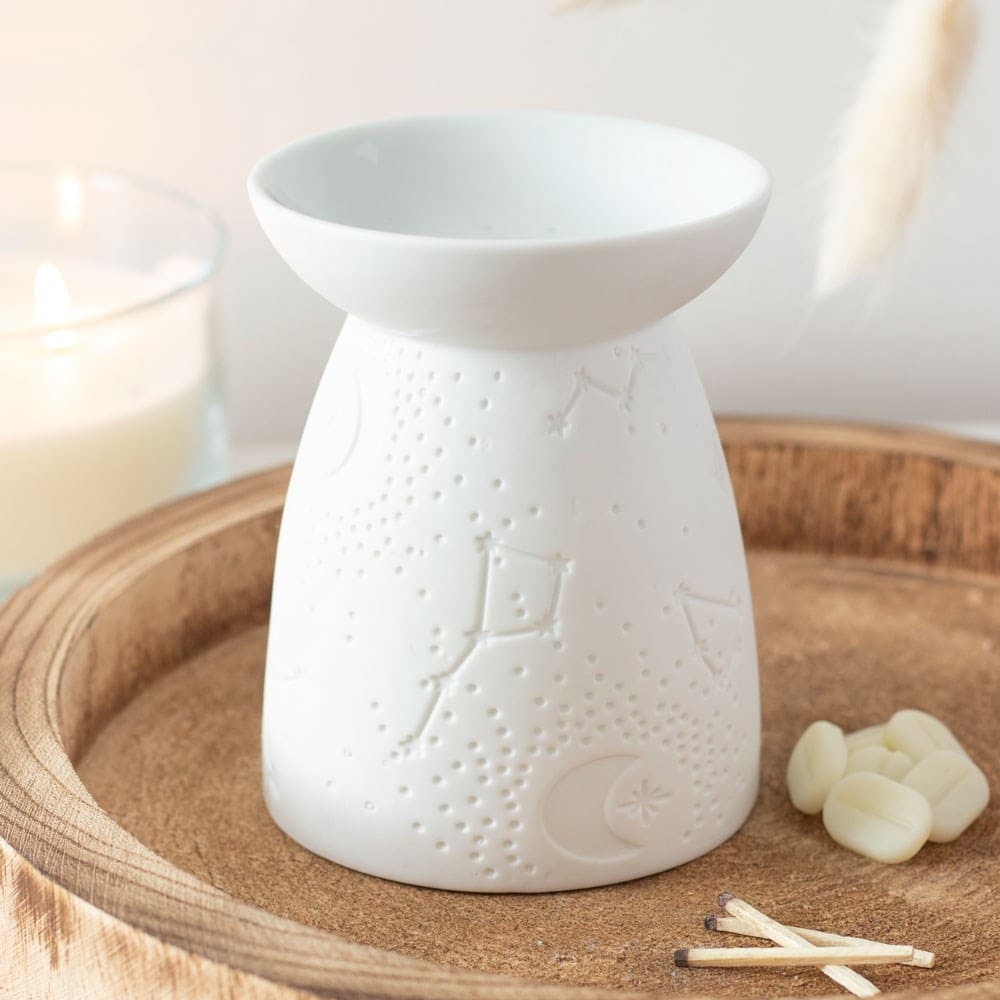 white wax melt and oil burner with a constellation design in a calm and relaxing setting