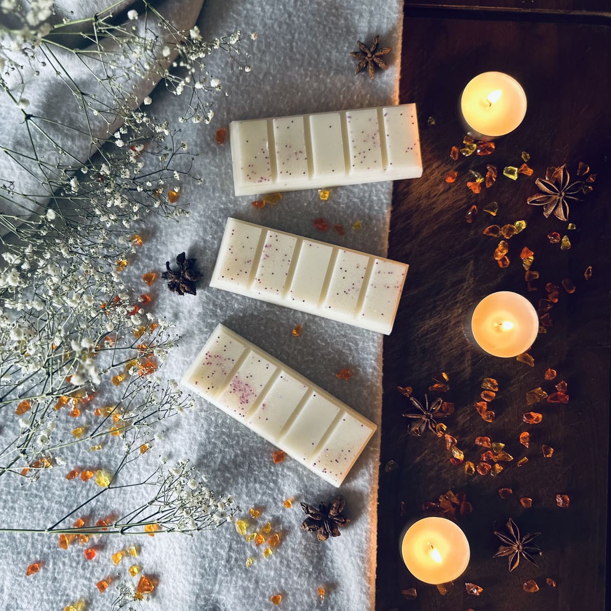 white soy wax melts on a wooly cashmere blanket surrounded by cosy tea lights