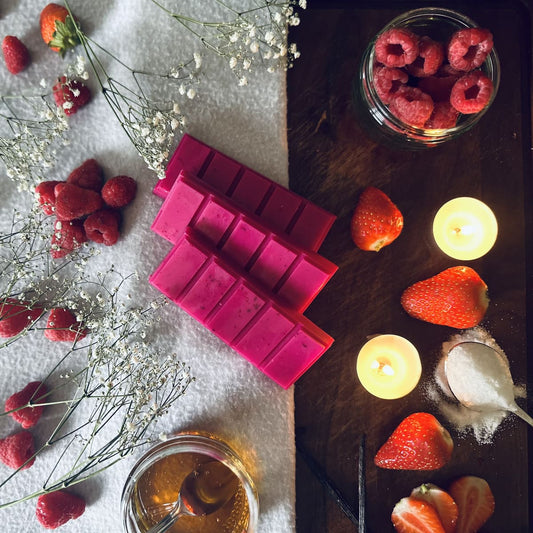 Pink candy floss scented soy wax melts surrounded by fresh raspberries, strawberries and honey