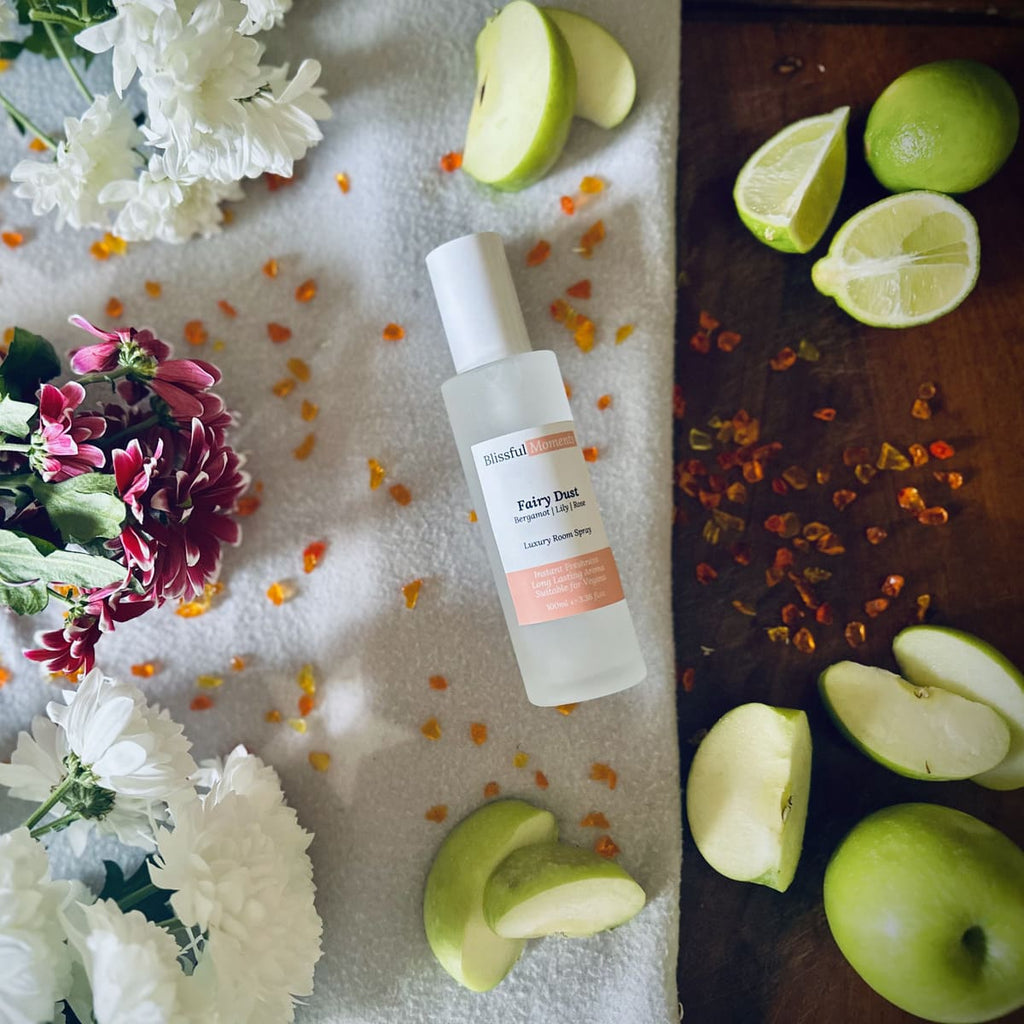 Fairy Dust scented luxury frosted glass room spray surrounded by fresh flowers, amber and green apples sitting on a cosy blanket
