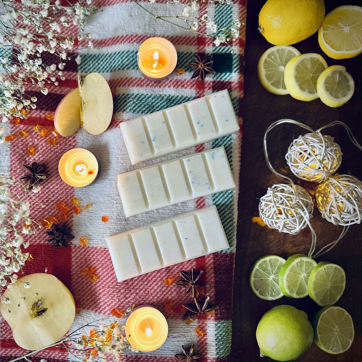 White coloured Frosty Lake scented wax melts on a red checkered cloth with lemons, candles, and christmas lights.