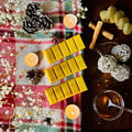 Golden Gingerbread scented wax melts on a Christmas checkered cloth with candles, flowers, caramel and cinnamon sticks.