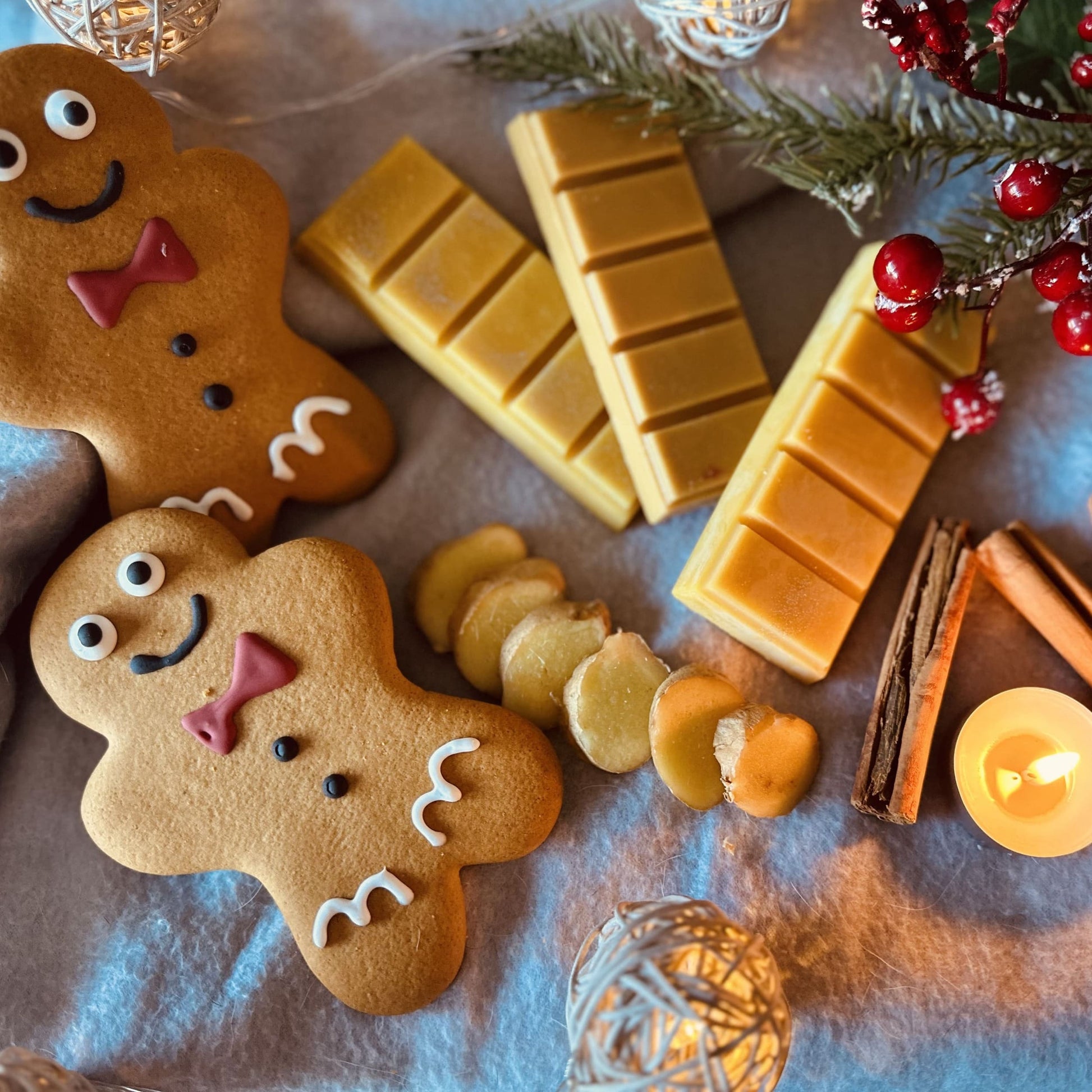 Gingerbread scented soy wax melts surrounded by gingerbread biscuits, cinnamon stick and tealights all sitting on a cosy blnaket