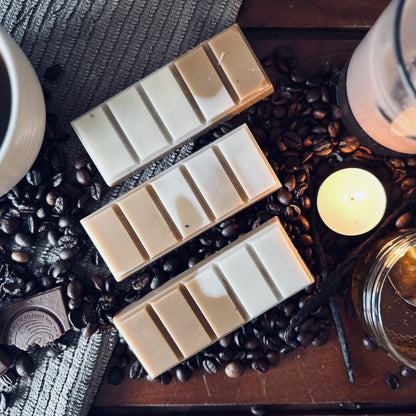 Brown and white coffee soy wax melts sitting on coffee beans surrounded bu black and irish coffes