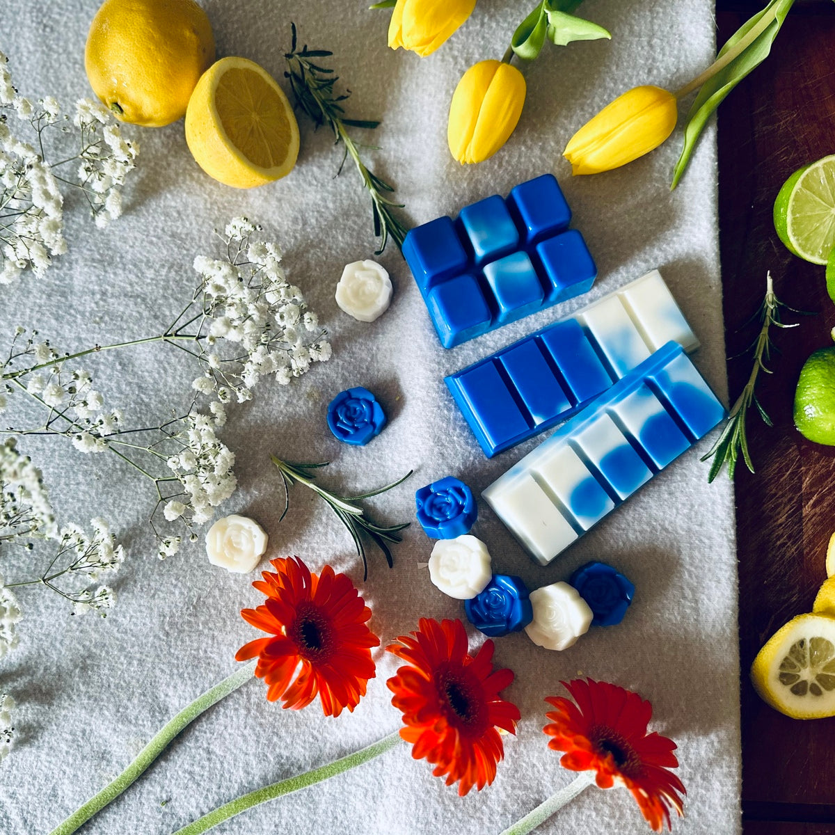 blue and white soy wax melts in a spa relaxing setting surrounded by fresh vibrant floral flowers and citrus fruits