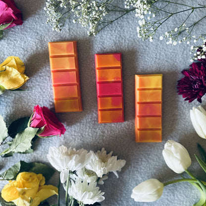 Red and orange soy wax melts surrounded by vibrant fresh floral roses and lilies