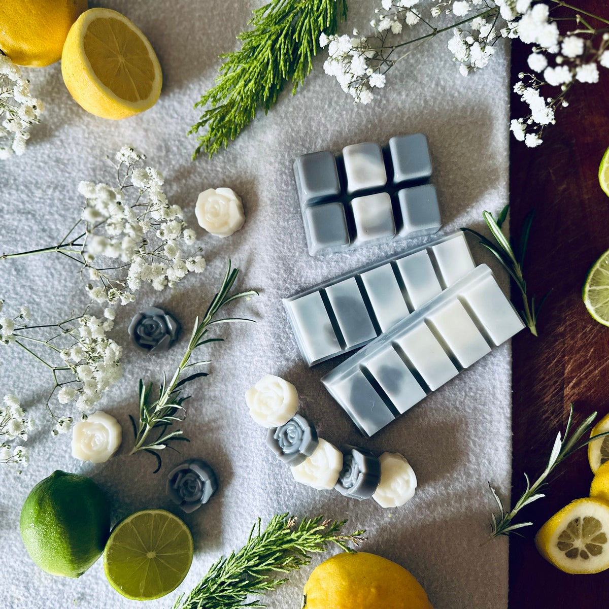 Grey and white soy wax melts in a spa relaxing setting surrounded by citrus fruits and white flowers