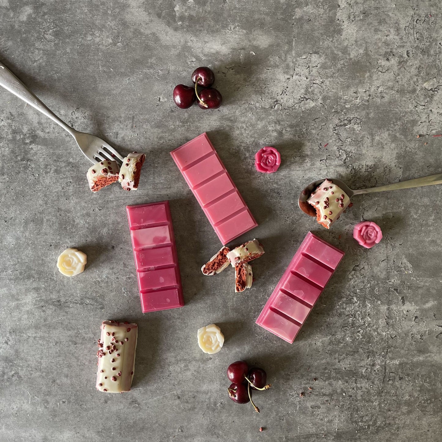 Red and white soy wax melts surrounded by red velvet cake and black cherries