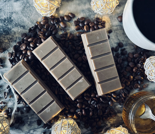 Brown soy wax melts setting on a bed of coffee beans with a fresh black coffee