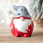 Santa styled Red gnome Gonk wax melt burner with a grey hat on a wooden surface with a Christmas background setting