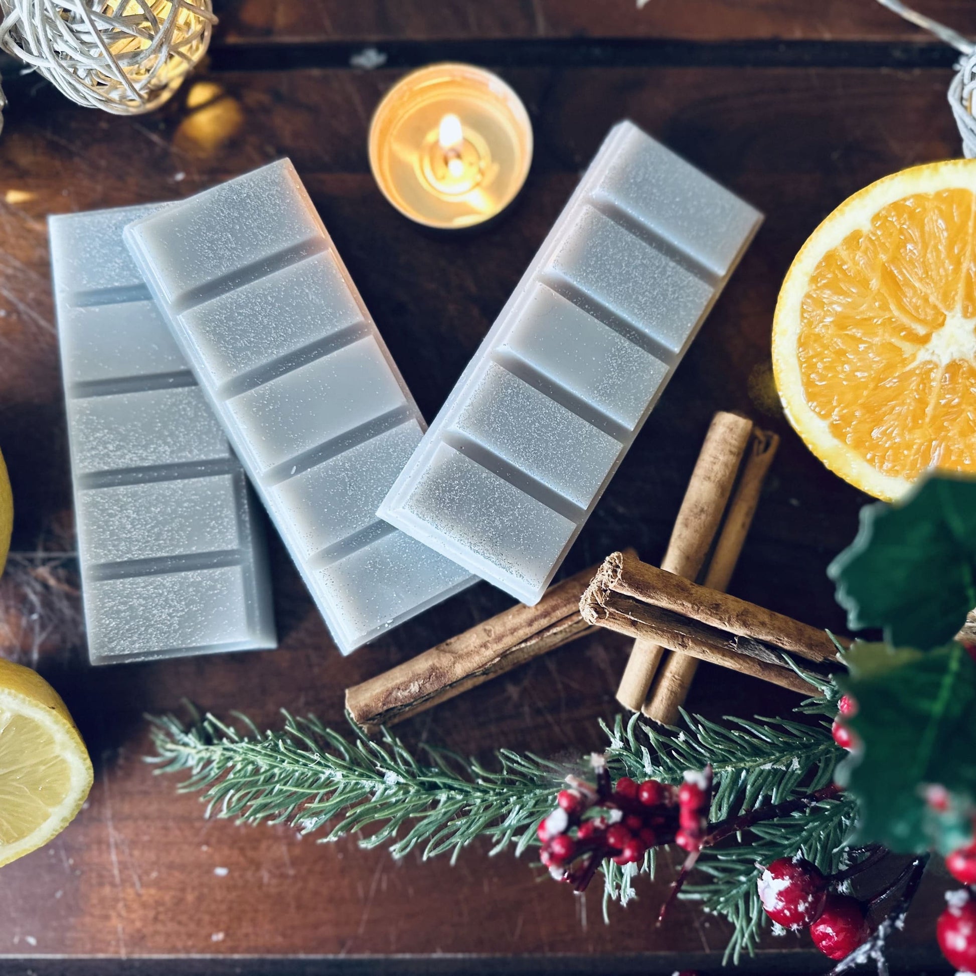 Grey sparkly soy wax melts surrounded by cinnamon sticks, citrus fruits and fairy lights