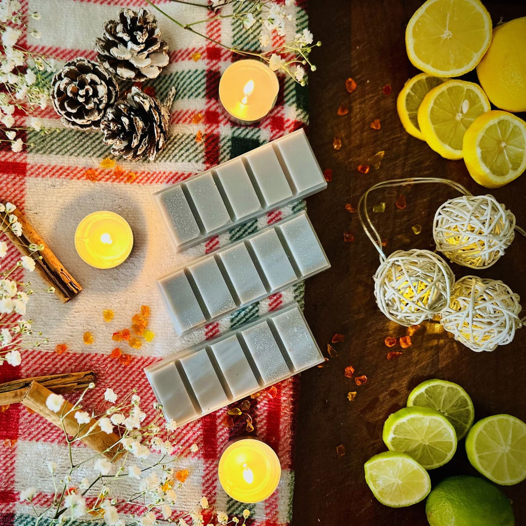 Grey StrayNight Snapbar Wax melts with Glitter on a checkered cloth with candles, lemons, and limes.