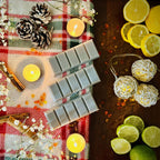 Grey StrayNight Snapbar Wax melts with Glitter on a checkered cloth with candles, lemons, and limes.