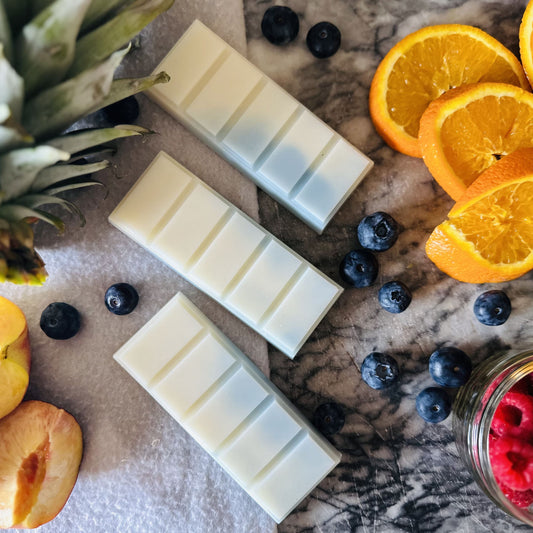 Blue and white soy wax melts in a tropical setting surrounded by pineapple, blueberries, oranges and peaches