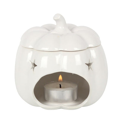 White pumpkin shaped burner with small stars cut out and a tealight lit in the wax melt burner