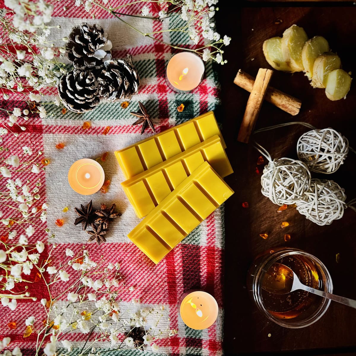 Golden Gingerbread scented snapbar wax melts on a checkered cloth with candles, pinecones, and Christmas decoration