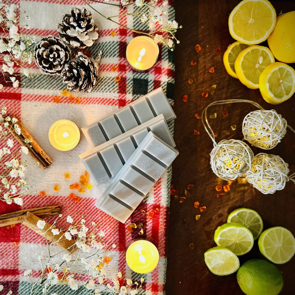 Grey Starry Night Snapbar wax melts in a Christmas decorative setting with candles, pinecones, and citrus fruits on a checkered cloth.