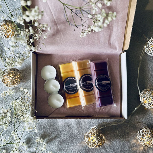 orange, cream and purple floral coloured soy wax melts in a lively presented gift box next to tea lights