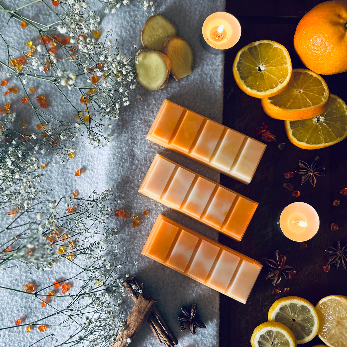 Mandarin and clove Christmas scented wax melts on dark wooden board surrounded by oranges, ginger, cinamon and star anise