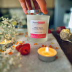 Hand taking the silver lid of the Snow Queen Candle  on a grey blanket surrounded by tea lights and raspberries.