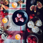 Three pink Cherry and Fig scented heart shaped wax melts in a black wax melt burner on a red festive checked tablecloth surrounded by figs, raspberries and christmas lights