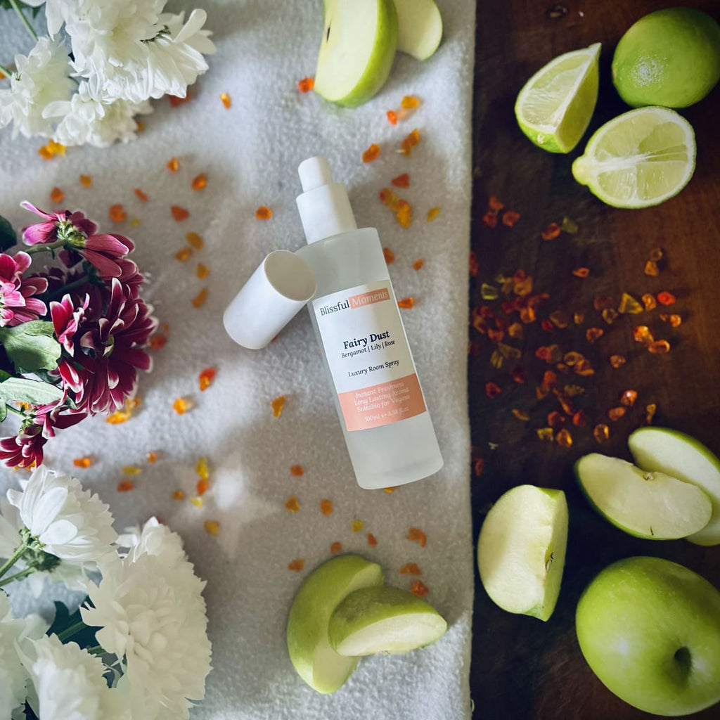 Fairy Dust scented luxury frosted glass room spray surrounded by fresh flowers, amber and green apples sitting on a cosy blanket