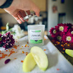 Forbidden Apple scented luxury frosted glass soy candle surrounded by fresh flowers, amber and green apples sitting on a cosy blanket