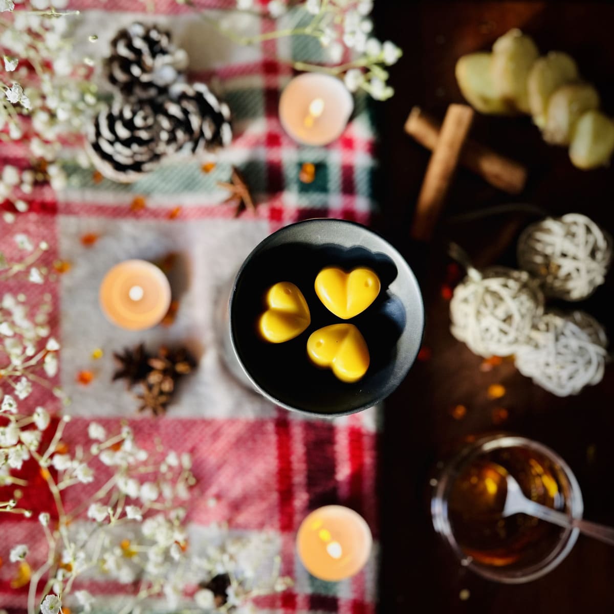 Heart-shaped Gingerbread scented wax melts in tealight burner dish on a festive table with candles, pinecones, and flowers.