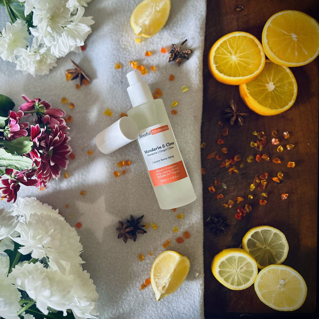 Luxury Mandarin & Clove scented rom spray surrounded by fresh flowers and citrus rooms sitting on a cosy blanket
