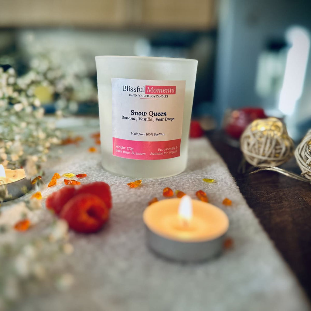 Snow Queen candles ona grey blanket surrounded by raspberries, tea lights and flowers