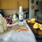 Beach House scented luxury frosted glass room spray surrounded by fresh flowers, amber and lemon sitting on a cosy blanket