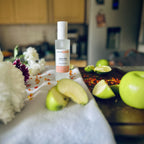 Fairy Dust scented luxury frosted glass room spray surrounded by fresh flowers, amber and green apples sitting on a cosy blanket