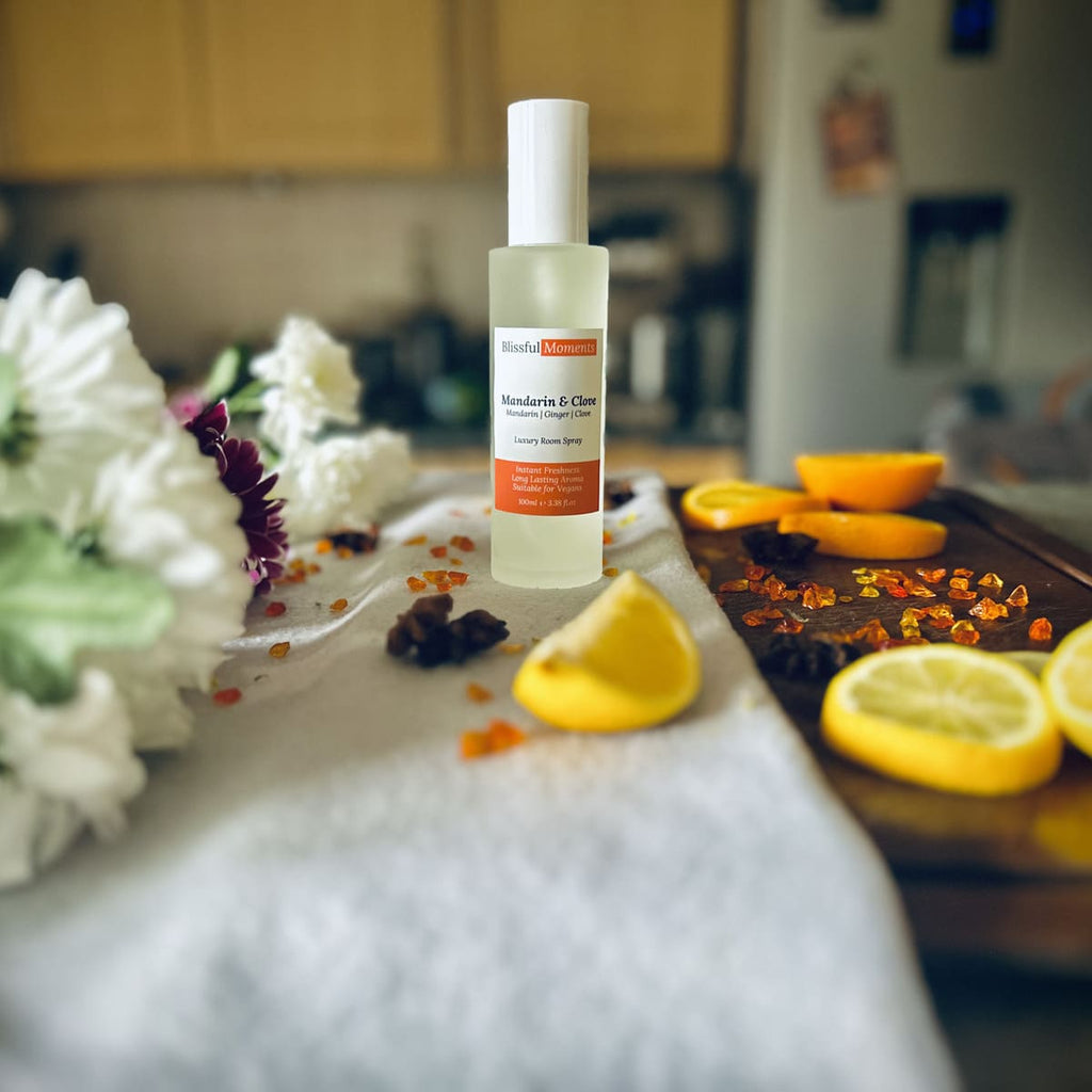 Luxury Mandarin & Clove scented rom spray surrounded by fresh flowers and citrus rooms sitting on a cosy blanket