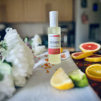 Luxury Pink Grapefruit room spray surrounded by citrus fruits and flowers sitting on a soft cosy blanket.