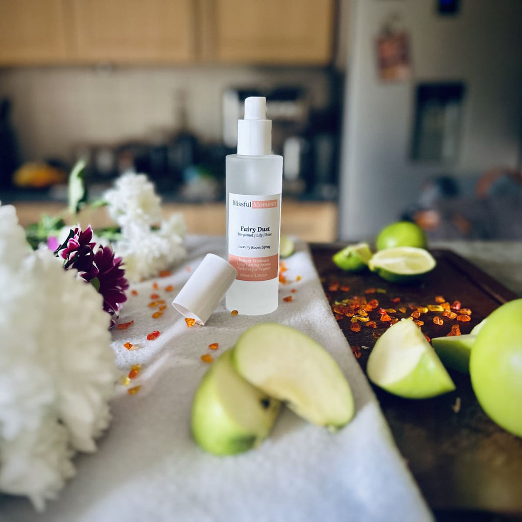 Fairy Dust scented luxury frosted glass room spray surrounded by fresh flowers, amber and green apples sitting on a cosy blanket