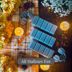Grey snapbar wax melts on a wooden surface with candles, pumpkins and flowers.